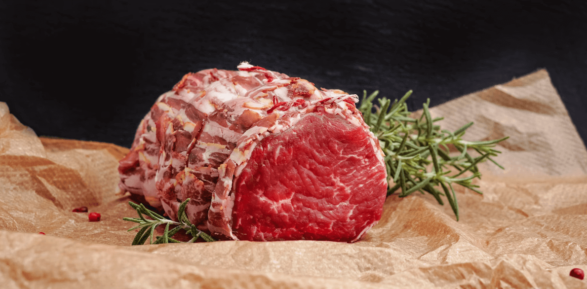 Lamb joint in brown paper with rosemary sprigs