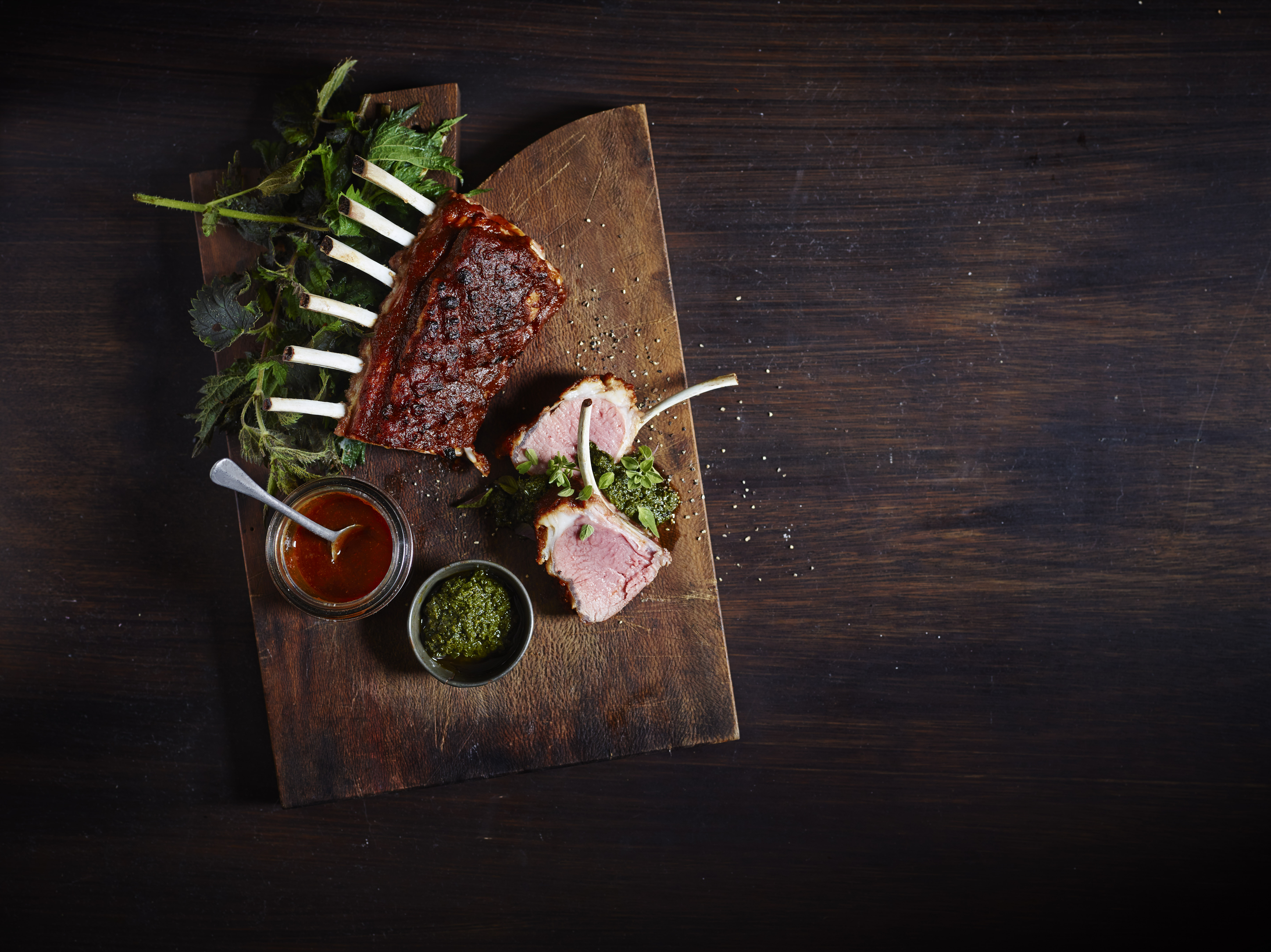 Rack of lamb on serving platter with herbs, chimichurri and glaze